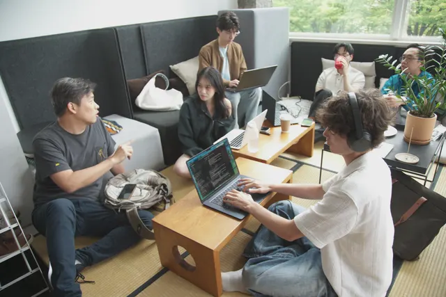 Builders arriving with laptops at low tables on tatami.