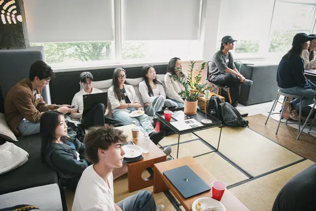 A lounge full of people working on laptops side by side.