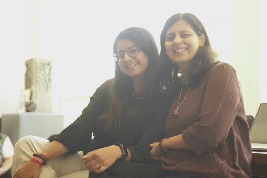 Two builders sitting close together on a couch, smiling at the camera.