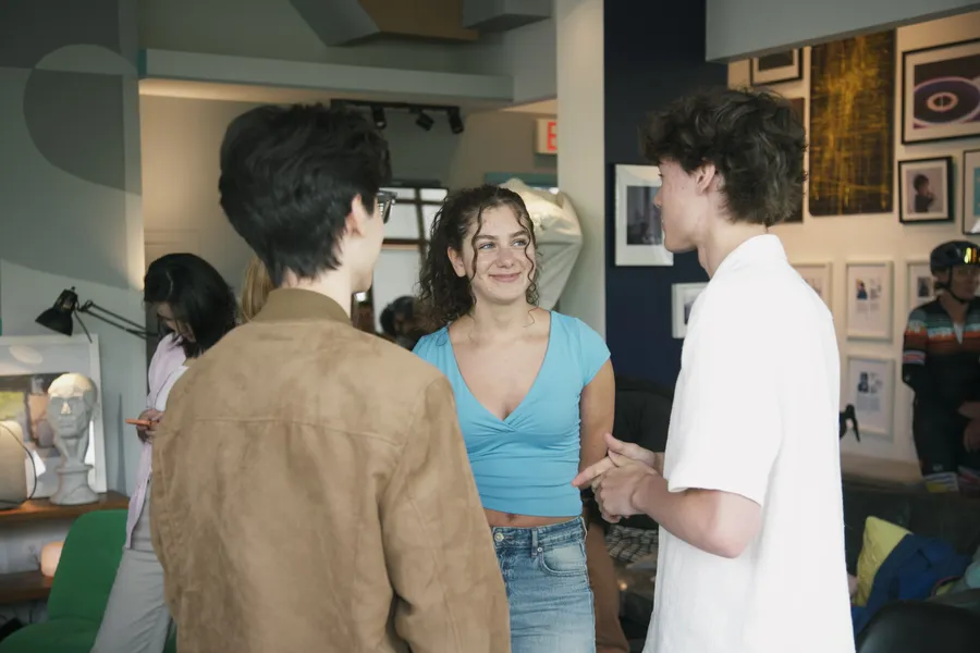 Three people chatting in a hallway lined with framed art.