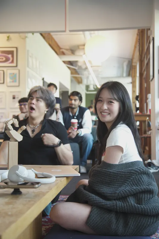 Two people laughing at a low wooden table.
