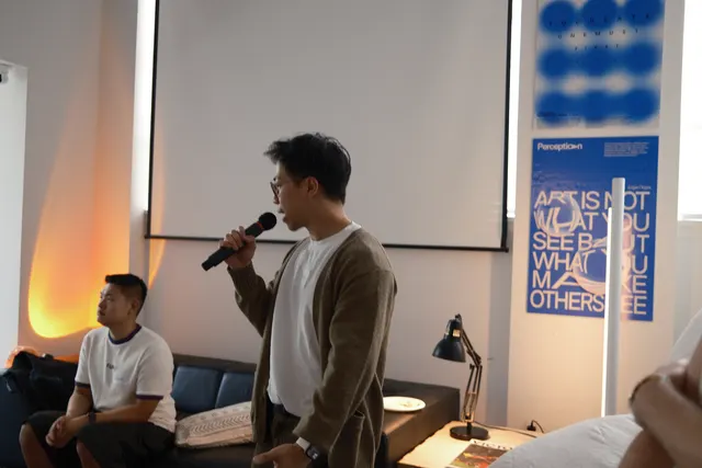 A builder on the mic showing the group what they worked on.